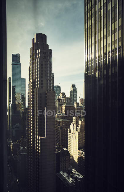 Through window of shiny skyscraper towers in dense district of New York city in sunlight — Stock Photo