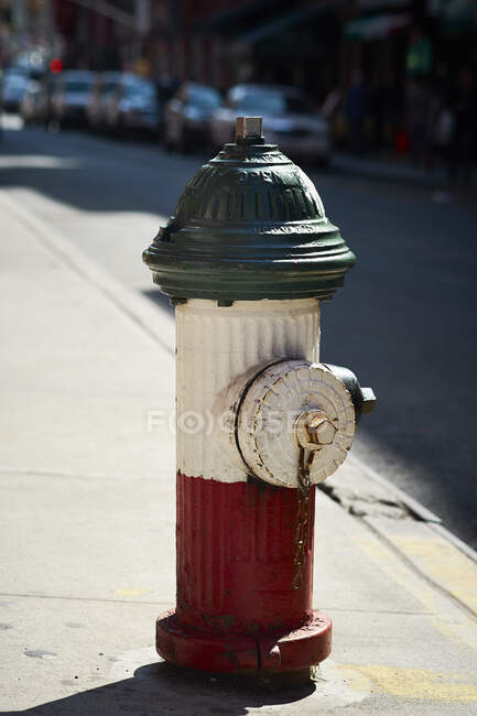 Ancienne bouche d'incendie rouge et blanche située sur le trottoir de la rue de New York par temps ensoleillé — Photo de stock