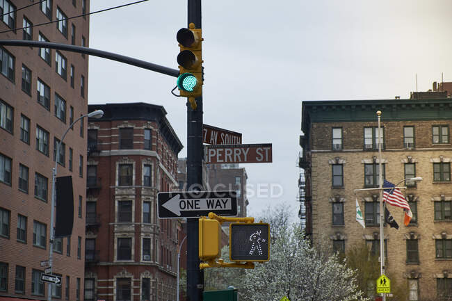 Baixo ângulo de sinalização com vários sinais de estrada e semáforo verde no antigo bairro de Nova York, com edifícios intemperizados no fundo — Fotografia de Stock
