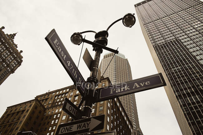 De dessous des panneaux de signalisation à sens unique sur le carrefour avec des bâtiments modernes en arrière-plan à New York — Photo de stock