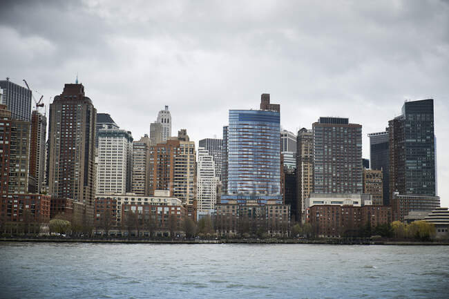 Contemporary skyscrapers of New York City seen from river against blue cloudy sky in sunny day — Stock Photo