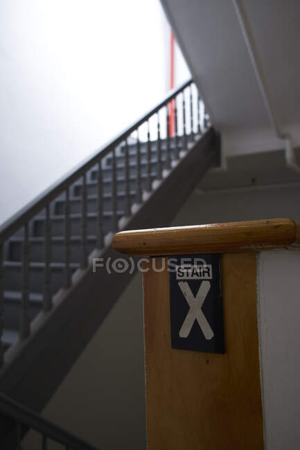 Señal de advertencia de información con la inscripción Escalera X colocada en la barandilla de la escalera en el edificio moderno - foto de stock