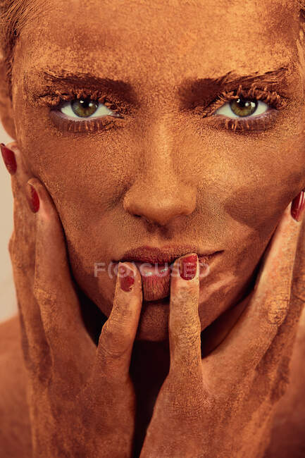 Junge schöne Frau mit Schokoladenpuder im Gesicht berührt die Haut und blickt in die Kamera — Stockfoto