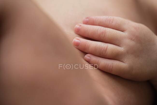 Closeup anonymous nude infant touching soft skin of body while resting at home — Stock Photo