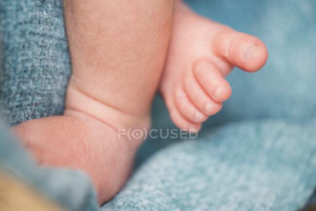 Closeup crop feet of anonymous baby lying on soft and warm blanket at home — Stock Photo