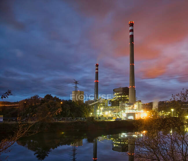 Industrierohre bei bewölktem Himmel nachts beleuchtet — Stockfoto