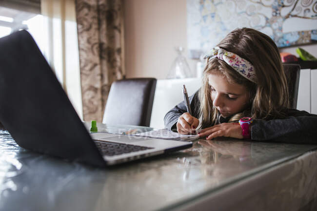 Girl doing homework assignment from laptop — Stock Photo