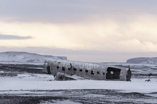 Vista lateral do jovem caminhando em carcaça de aeronaves abandonadas enquanto viaja pela Islândia — Fotografia de Stock
