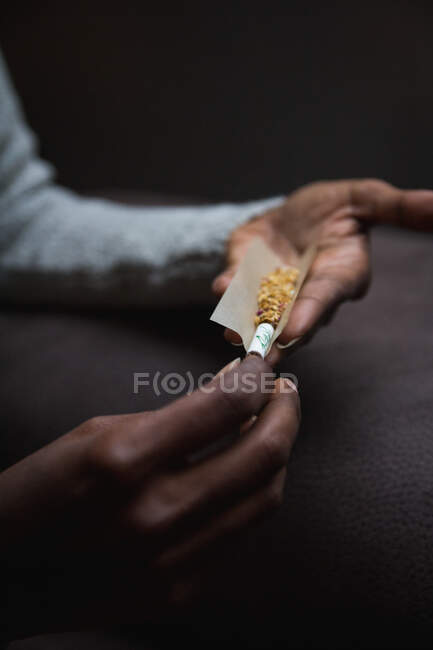 Обрізані невпізнавані етнічні руки, що завантажують марихуану сигарету — стокове фото