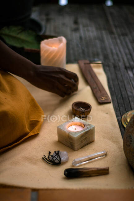 Возделывайте неузнаваемую этническую женскую руку вблизи традиционных аутентичных фонарей со свечами, кристаллами и ароматическими палочками во время духовного ритуала — стоковое фото
