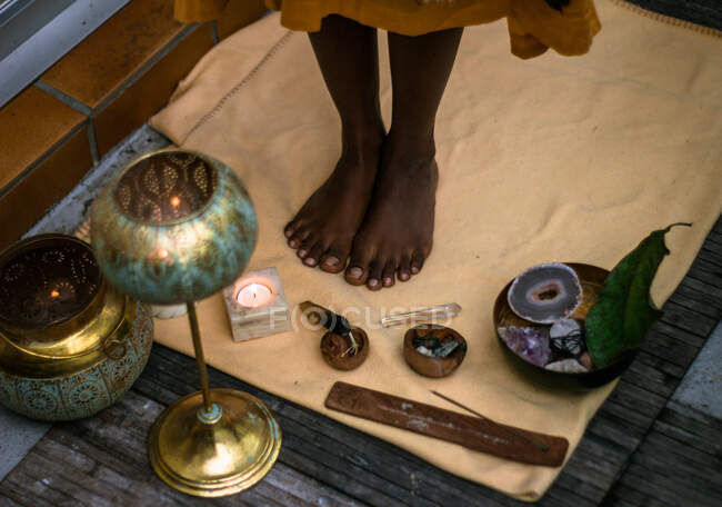 D'en haut de la récolte méconnaissable ethnique femelle avec pieds nus debout près des lanternes authentiques traditionnelles avec des bougies et des bâtons aromatiques pendant le rituel spirituel — Photo de stock