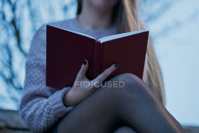 Close up view of young woman freelancer in soft jumper and shirt black skirt checking schedule in notepad while resting on wooden bench in spring park — Stock Photo
