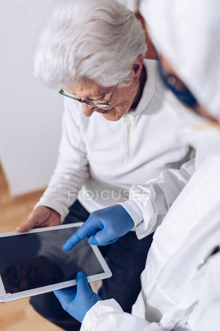 Врач объясняет медицинскую информацию пожилым пациентам дома во время карантина коронавируса — стоковое фото