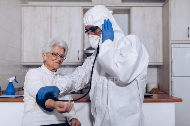 Home care specialist checking blood pressure of patient at home — Stock Photo