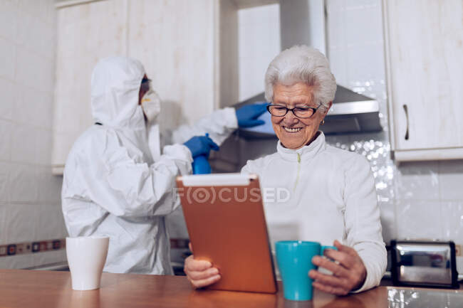Home care employee helping senior client at home during quarantine — Stock Photo