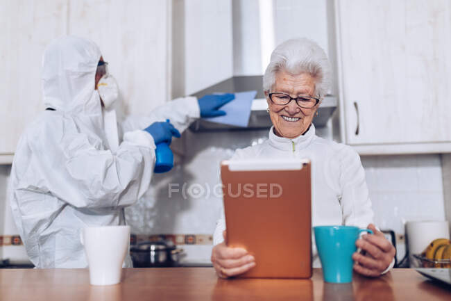 Home care employee helping senior client at home during quarantine — Stock Photo