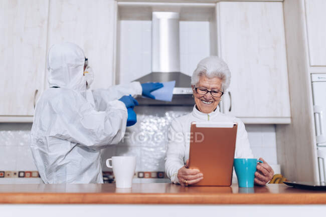 Collaboratore domiciliare che aiuta il cliente anziano a casa durante la quarantena — Foto stock