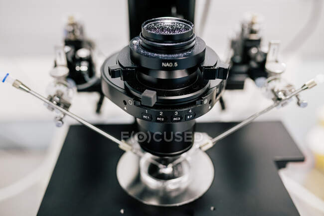 Lente de máquina moderna sobre placa de Petri e manipuladores durante o processo de fertilização do óvulo no laboratório contemporâneo de clínica — Fotografia de Stock