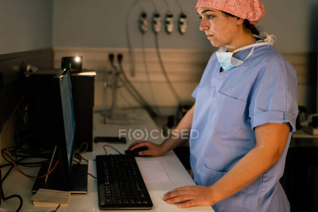 Visão lateral do médico feminino usando computador durante o trabalho em laboratório do hospital moderno — Fotografia de Stock