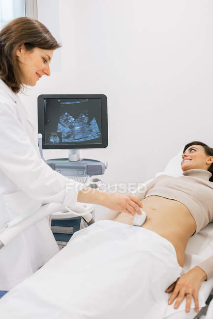 Kornmediziner macht Sonogramm für glückliche schwangere Frau während der Arbeit in einer modernen Fruchtbarkeitsklinik — Stockfoto