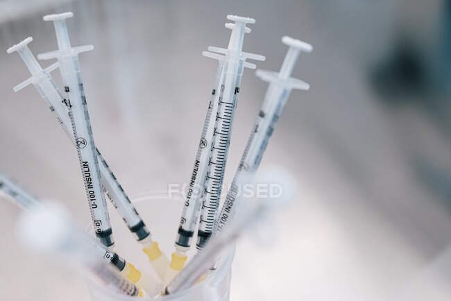 D'en haut tas de seringues avec des médicaments hormonaux placés dans un récipient sur la table dans le laboratoire de la clinique de fertilité — Photo de stock