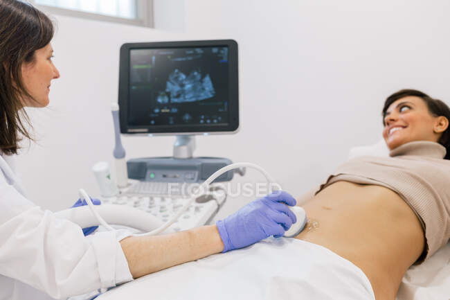 Kornmediziner macht Sonogramm für glückliche schwangere Frau während der Arbeit in einer modernen Fruchtbarkeitsklinik — Stockfoto