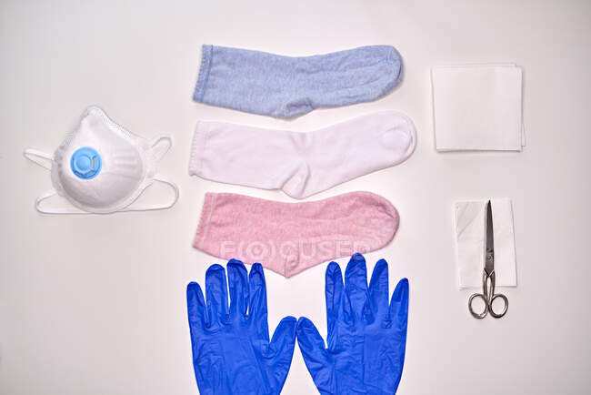 Vista superior de los calcetines guantes servilleta y tijeras para hacer máscara de tela durante el período de cuarentena de coronavirus para la protección - foto de stock
