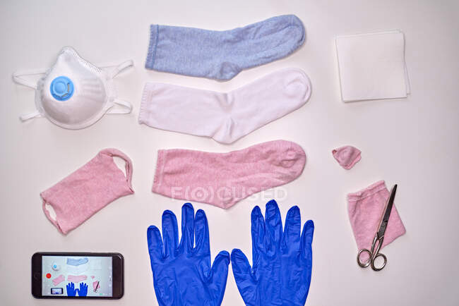 Верхний вид носков перчатки смартфона салфетки и ножницы, чтобы сделать ткань маску во время карантинного периода коронавируса для защиты — стоковое фото