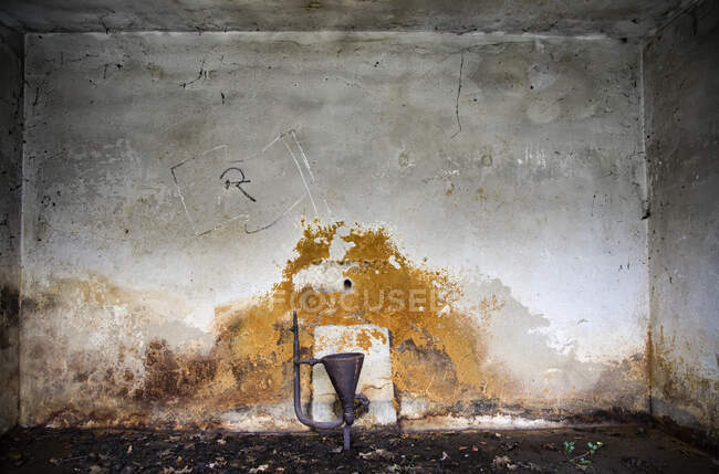 Teil alter rostiger Metallausrüstung in der Nähe einer gröbsten Betonwand in einem verlassenen Industriegebäude platziert — Stockfoto