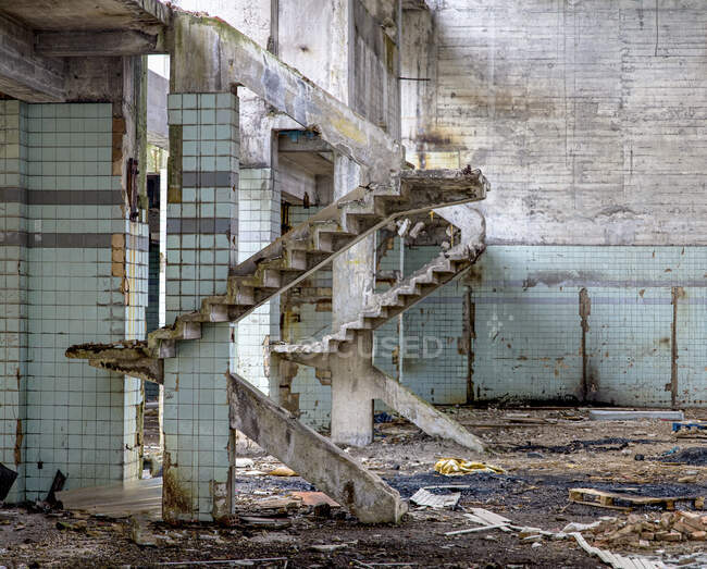Бетонные стены и остатки лестниц в старом заброшенном промышленном здании с грязным грунтом — стоковое фото