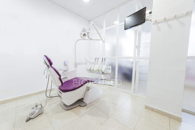 Interior of modern light empty dental office with chair and medical instruments and equipment placed around and white sink near wall — Stock Photo