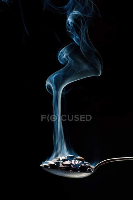 Colher metálica com grãos de café frescos em fundo preto — Fotografia de Stock