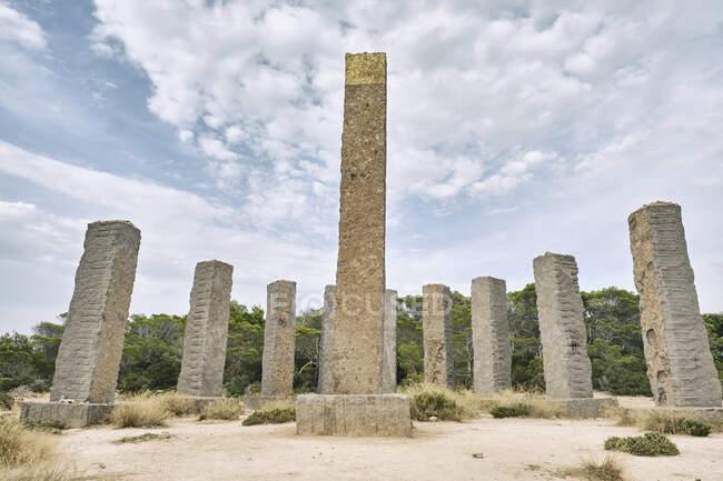 Colunas de pedra envelhecidas localizadas em território arenoso cercado por floresta tropical verde no dia nublado em Ibiza — Fotografia de Stock