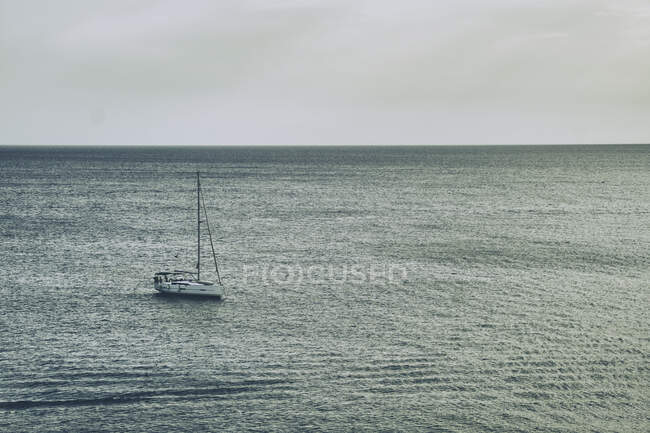 Одинокий парусник, плывущий по спокойной океанской воде — стоковое фото