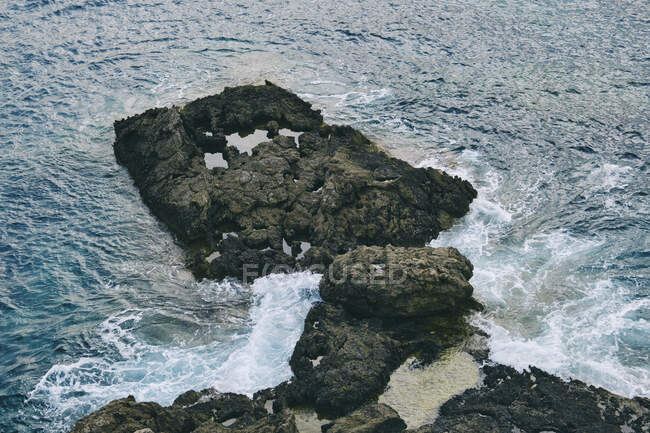 Wellen stürzen in stürmischem Ozean über hohe Felsklippen — Stockfoto