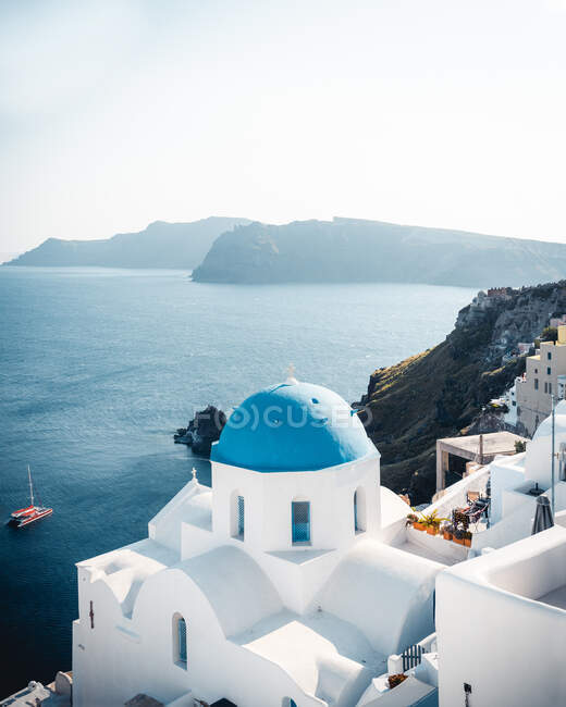 White houses on picturesque rocky seashore with calm sea in Santorini on hot summer day — Stock Photo