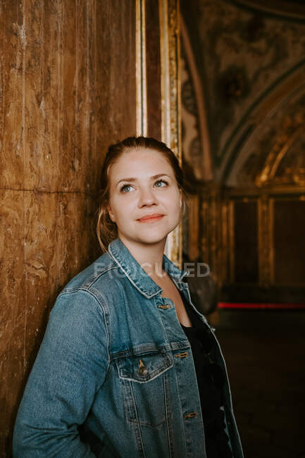 Sorridente giovane viaggiatore femminile positivo in abiti casual in piedi vicino alla porta di legno di edificio invecchiato e guardando verso l'alto mentre si passa il tempo ad esplorare attrazioni di Istanbul — Foto stock