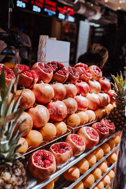 Ripe red colorful pomegranates and sweet pineapples on display at fruit shop counter in market in Istanbul on summer sunny day — Stock Photo
