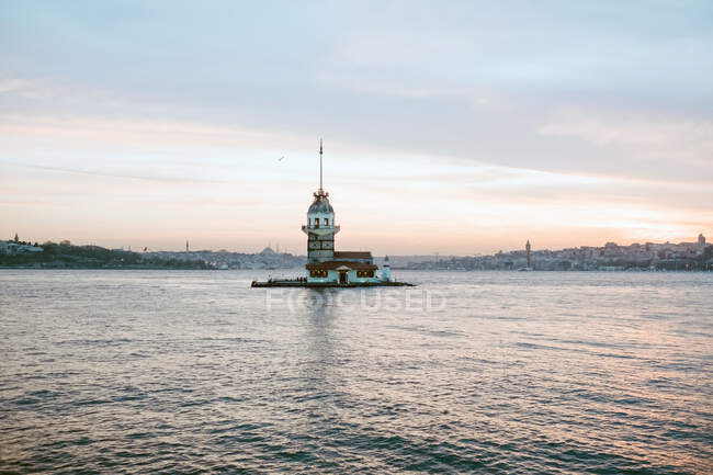 Далекий маленький маяк в центре спокойного чудесного моря против облачного закатного неба теплым вечером летом в Стамбуле — стоковое фото