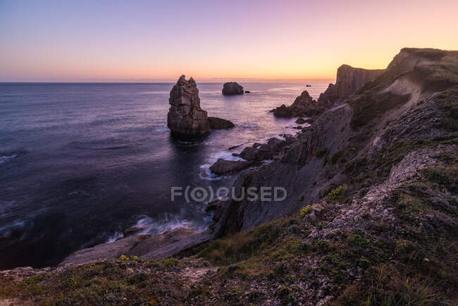 Meeresküste mit Felsen, die über dem Wasser aufragen und wunderschönem Sonnenaufgangshimmel — Stockfoto