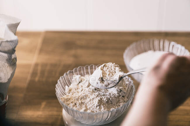 De cima cultura fêmea anônima pesando farinha de trigo em balanças eletrônicas enquanto prepara ingredientes para receita de pastelaria caseira na cozinha — Fotografia de Stock