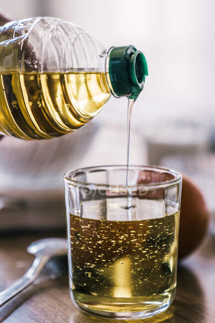 Анонимные урожая женщина заливки растительного масла в меру стекла помещены на стол с ингредиентами для рецепта во время приготовления выпечки у себя дома — стоковое фото