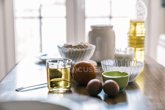 Інгредієнти для приготування домашніх ароматних апельсинових кексів, розміщених на дерев'яній стійці біля вікна в сучасній кухні — стокове фото