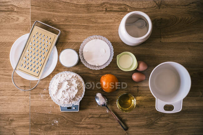 Vista superior de la escala electrónica con harina de trigo e ingredientes para deliciosos magdalenas caseras aromáticas en la cocina - foto de stock