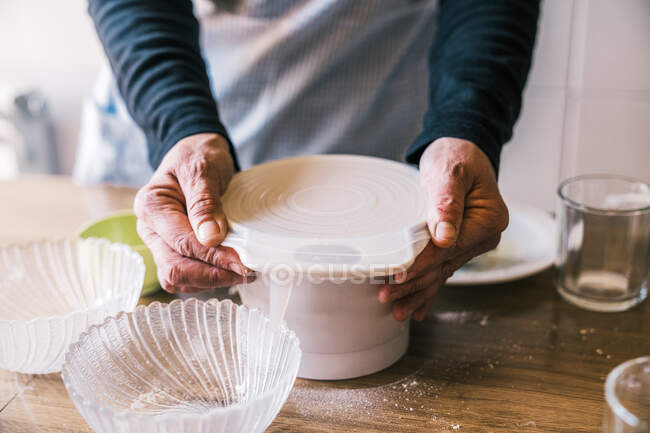 From above of crop female with plastic bowl standing at table in kitchen and preparing dough for cooking muffins — Stock Photo