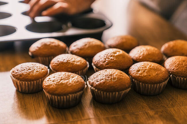 De cima delicioso pronto para comer muffin em caixa de papel colocado em mesa de madeira na cozinha — Fotografia de Stock