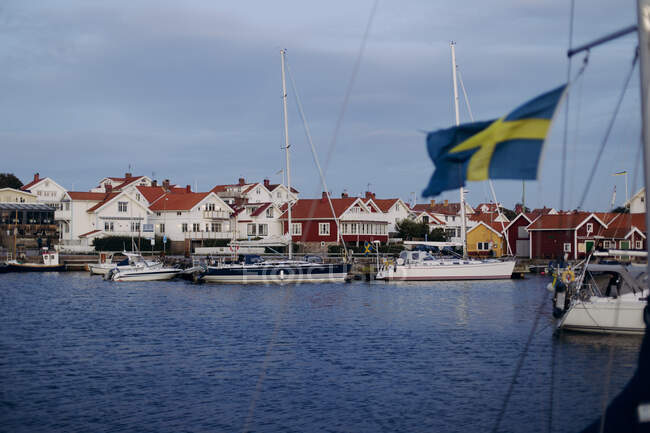 Yachthafen mit weißen Yachten Parkplatz am Pier auf ruhigem Meerwasser vor dem Hintergrund der Küstenstadt mit schönen Häusern und wolkenverhangenem Himmel in Schweden — Stockfoto