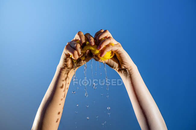 Persona senza volto strizzando straccio bagnato durante la pulizia della casa su sfondo blu in studio — Foto stock