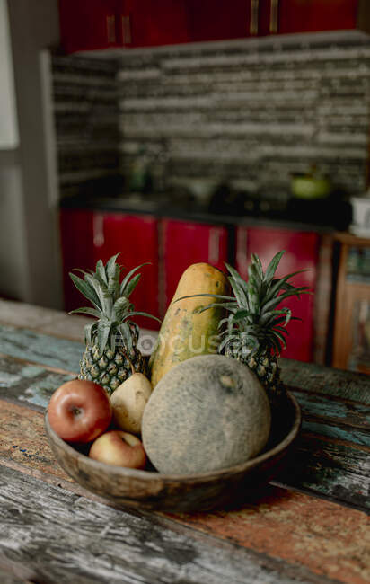 Ciotola di legno con melone fresco, mele e ananas posto sul tavolo della terrazza estiva a Bali — Foto stock