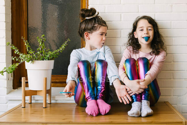Deux sœurs souriantes sortant une langue bleue après avoir mangé une gomme à bulles bleue — Photo de stock
